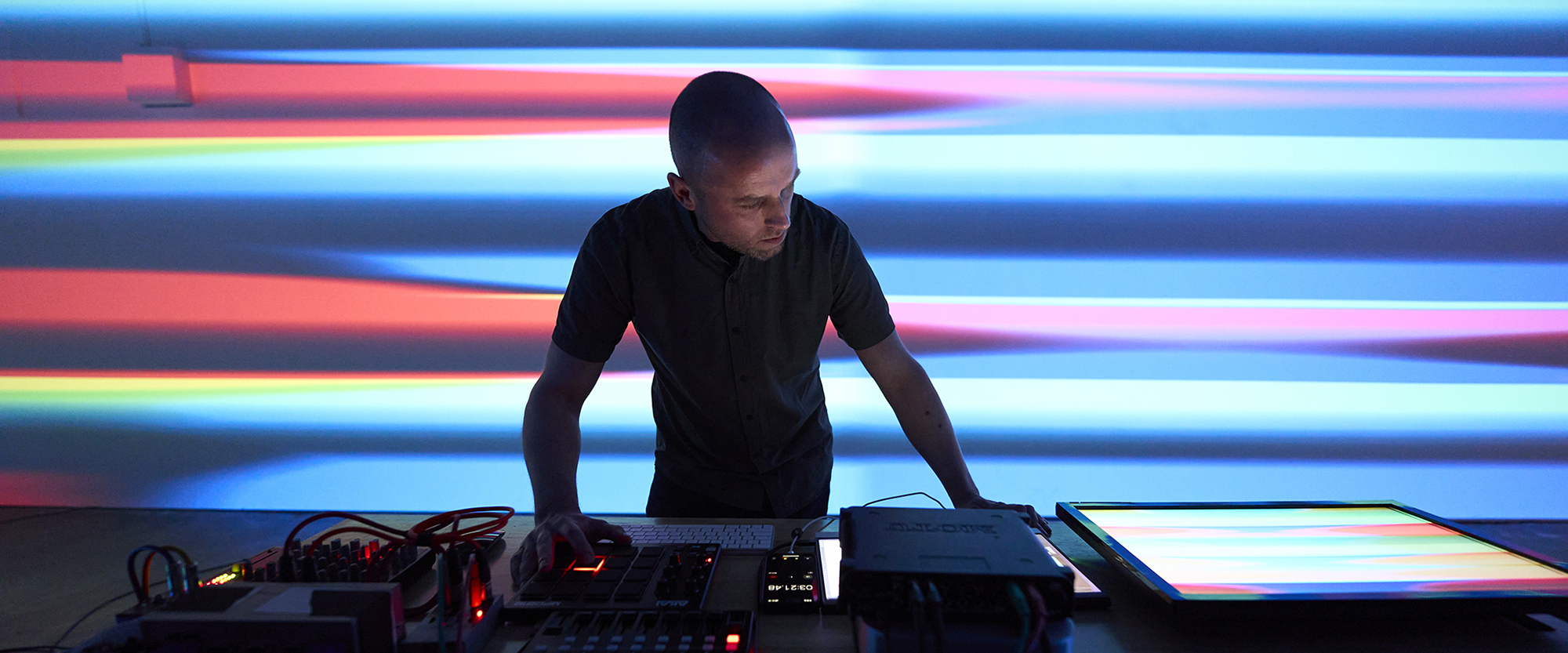 James Connolly performing with electronic equipment driving projected video behind him.