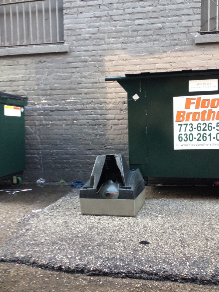 A cathode ray tube television broken and face down in an alley.