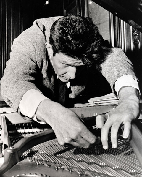 Portrait of John Cage modifying a piano for one of his Prepared Piano compositions.