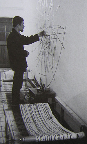 A man dragging a tape playhead across electromagnetic audio tape attacked to a wall for Nam June Paik's Random Access artwork.